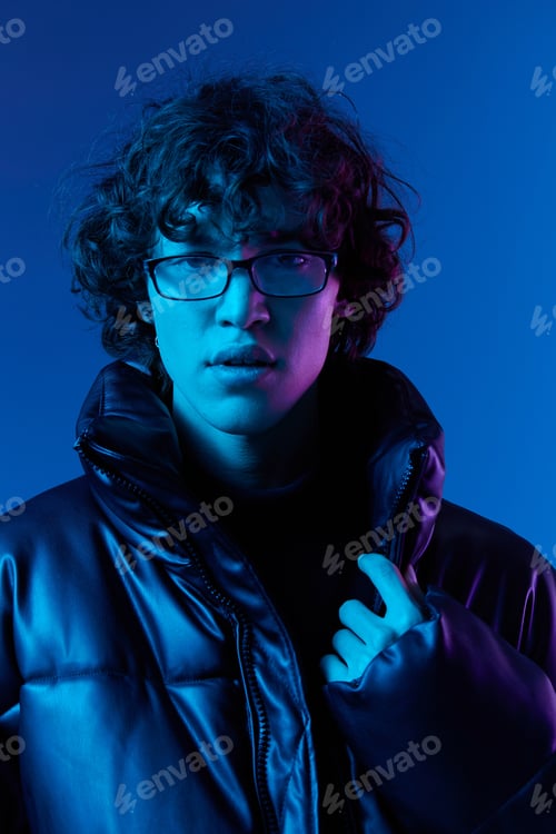 Preview: Man in winter jacket model poses in glasses smile, hipster lifestyle, portrait blue background