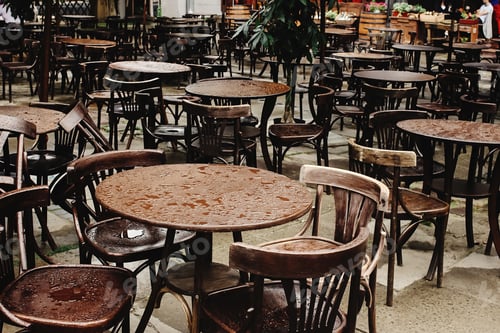 Preview: stylish wooden chairs and tables empty at rainy day on streets of europe city