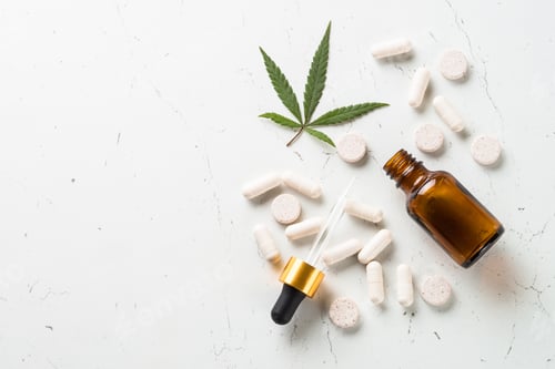 Preview: CBD oil in glass bottles and cannabis leaves at white table