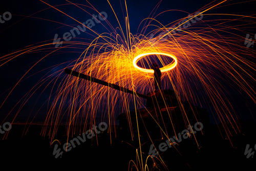 Preview: Long exposure of sparks radiating from a spinning wad of steel wool, against a backdrop of darkness