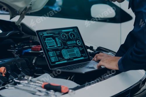 Car mechanic using laptop computer examining tuning fixing repairing car engine in garage.
