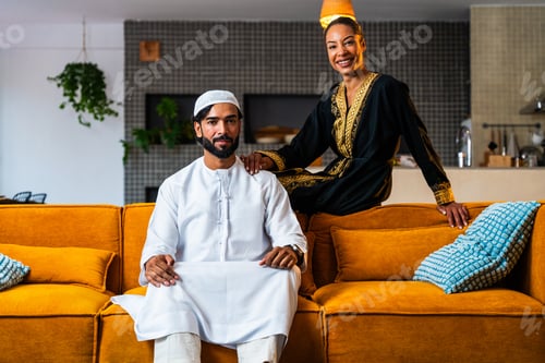 Preview: Happy beautiful young arab couple with emirati clothing together at home