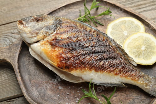 Preview: Tasty roasted dorado fish and spices on wooden table, closeup. Homemade seafood dish
