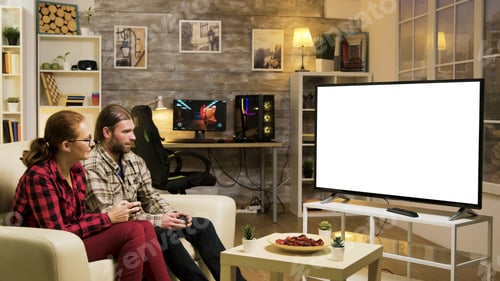 Preview: Cheerful couple sitting on couch playing video games