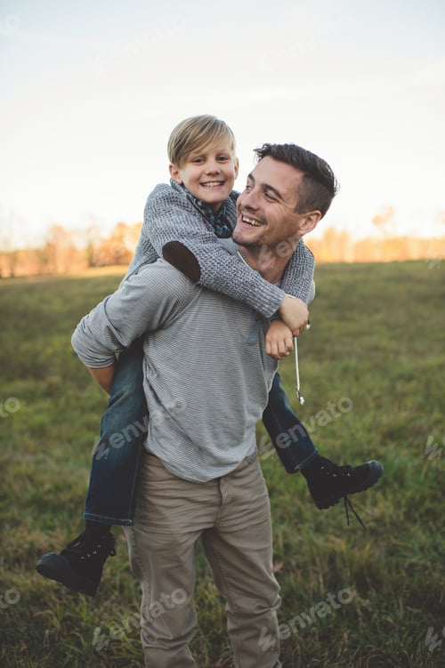 Preview: Boy getting piggy back from father in field