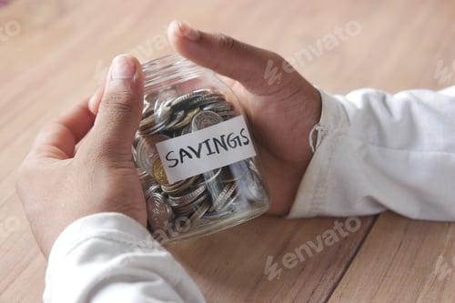 Preview: Savings Jar Held on Wooden Tabletop