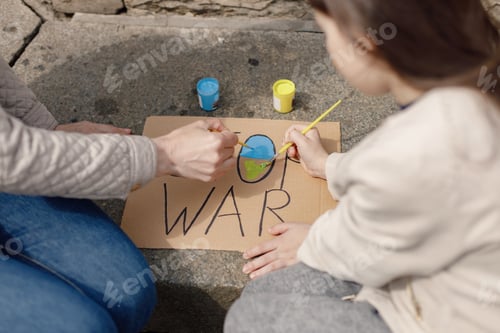 Preview: Woman and girl painting a poster Stop War with blue and yellow colors