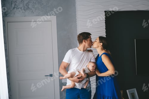 Preview: Romantic Kiss Between Parents Holding Their Infant