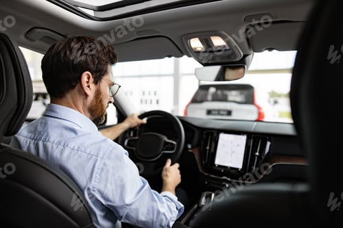 Preview: Businessman test driving car in dealership showroom
