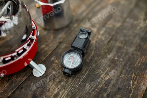 Preview: Compass, gas burner, coffee maker on the wooden table outdoor, Travel camping equipment