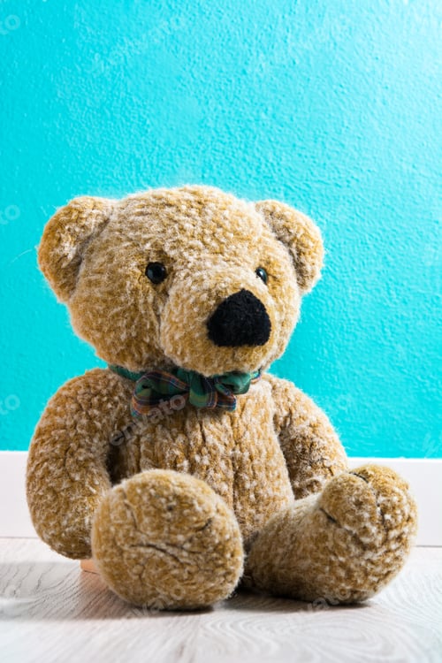 Preview: Adorable teddy bear sitting against turquoise wall