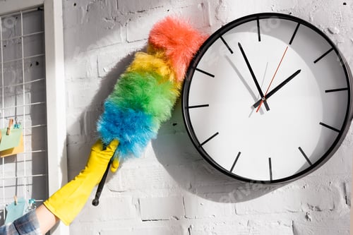 Preview: Cropped view of woman cleaning clock with dust brush