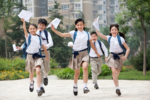Preview: Cheerful schoolchildren in uniform with results lists in hands