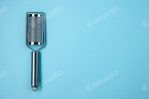 Preview: Top view of stainless kitchen tool on the right side on pastel blue wave background with free space