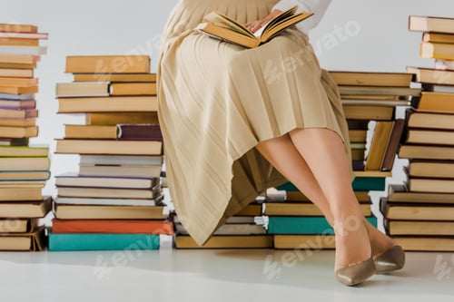 Preview: close up of woman reading and sitting on pile of books