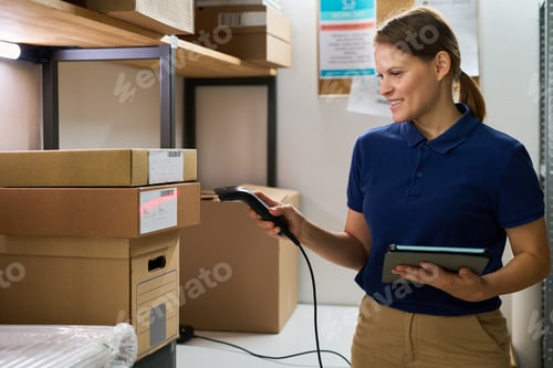 Preview: Young Adult Caucasian Woman Scanning Packages While Holding Digital Tablet