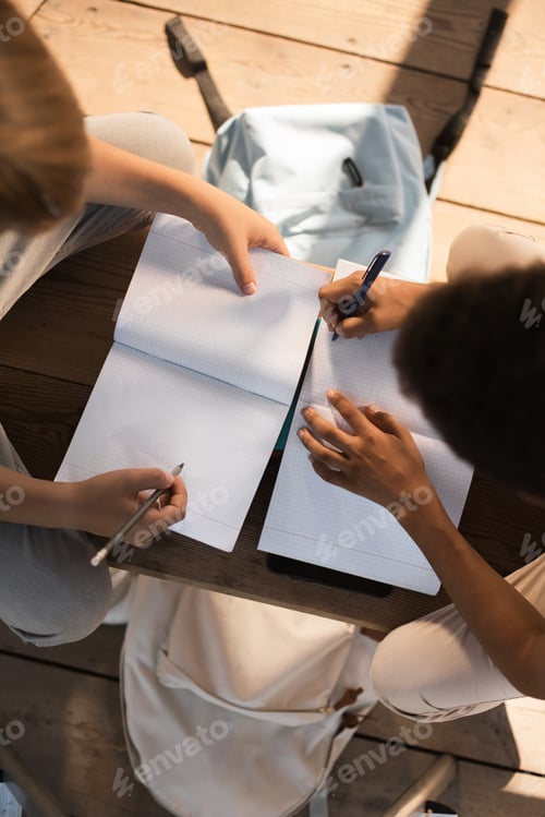 Preview: overhead view of teenage boys taking notes while studying on bench