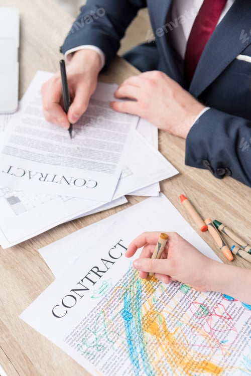 Preview: Businessman drawing on business papers with son at office