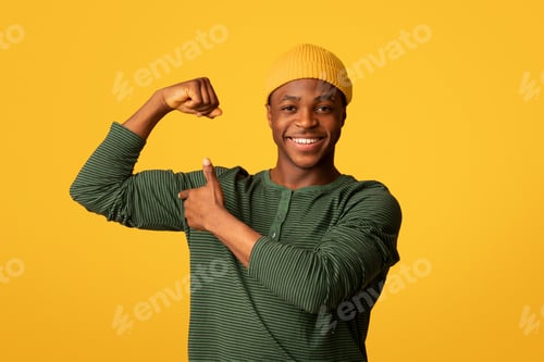 Preview: Cheerful Young Black Man Pumping Fist And Pointing At His Biceps