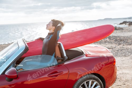 Preview: Woman with surfboard on the car near the ocean