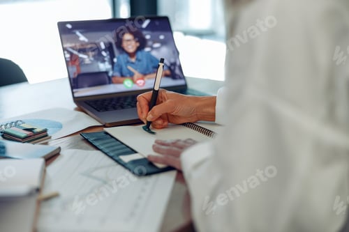Preview: Close up of woman freelancer have video conference with client and making notes sitting near