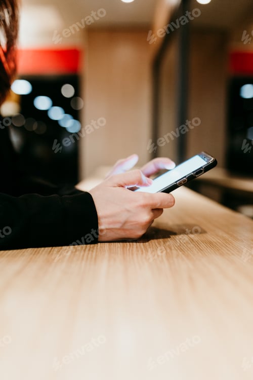 Preview: close up woman using mobile phone in a cafe or restaurant indoors. Unrecognizable person lifestyles
