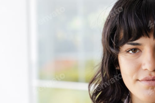 Preview: Close-up of woman with dark hair looking confidently at camera indoors