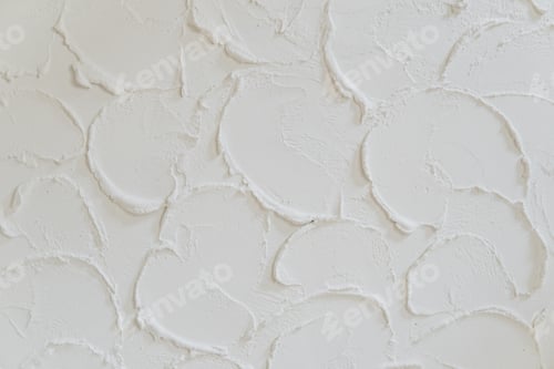 Preview: Photography of a wall covered in white paint or cement with a textured, uneven surface.