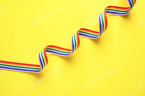 Preview: Rainbow ribbon on yellow background, top view. Gay symbol