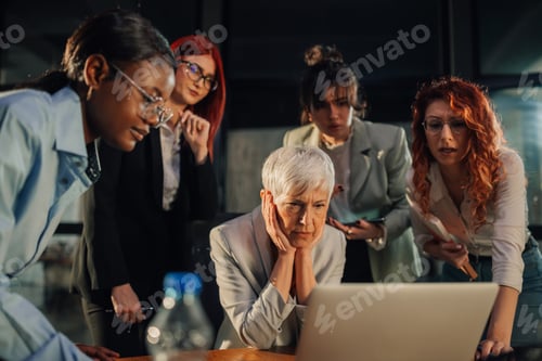 Preview: Senior businesswoman nervously looking at report with interracial team