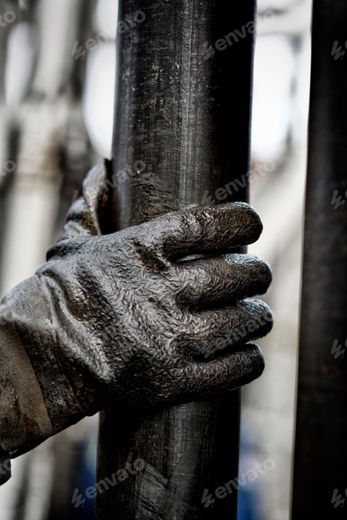 Preview: Human hand wearing a pair of gloves on oily drilling pipe