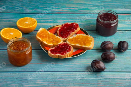 Preview: Orange and plum confiture in glass jars with toast breads