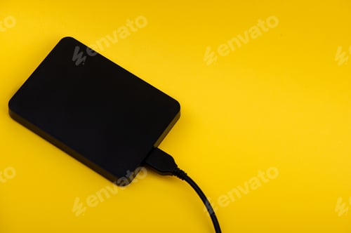 Preview: Black external portable hard disk drives isolated on yellow background