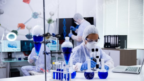 Preview: Female scientist in protection equipment adjusting her microscope