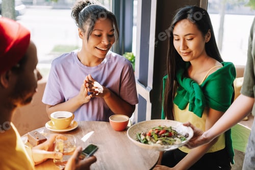 Preview: Diverse group of friends enjoying food and drinks at a cafe