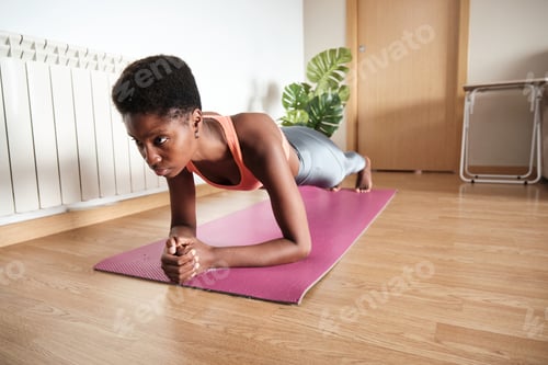 Preview: Black sportswoman doing plank exercise on mat