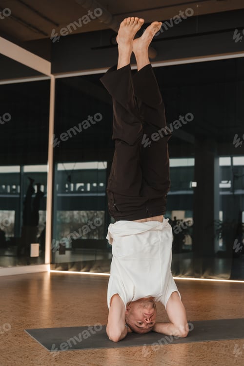 Preview: An athletic young man does exercises in the fitness room. A professional guy does yoga in the gym