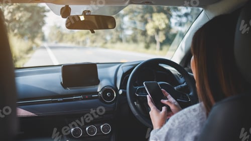 Preview: Closeup image of a woman using mobile phone while driving a car