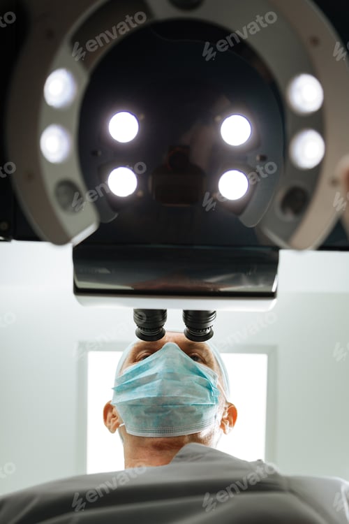 Preview: Low angle of a professional ophthalmologist looking into the microscope