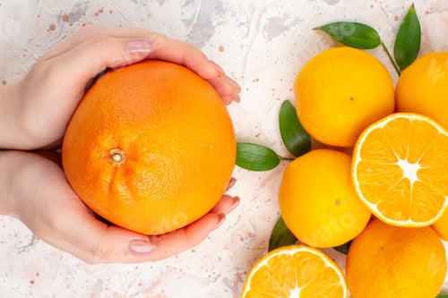 Preview: top close view fresh mandarines cinnamon sticks cut orange in woman hands on bright isolated
