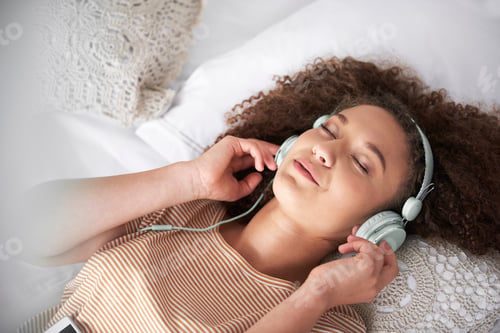 Preview: Teenage girl listening to music and lying on the bed