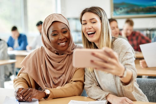 Preview: Happy female college students taking selfie and having fun in the classroom.