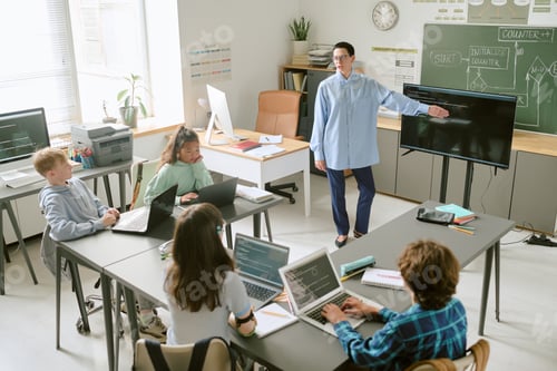 Preview: Middle Aged Caucasian Woman Teaching Diverse Teenagers Using Laptops in Classroom
