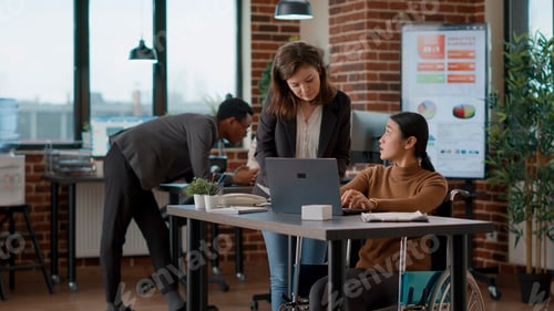 Preview: Woman with disability talking to colleague about business charts