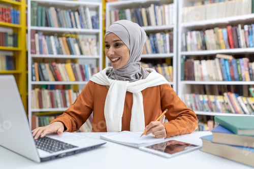 Preview: Smiling woman in hijab studying at library with laptop