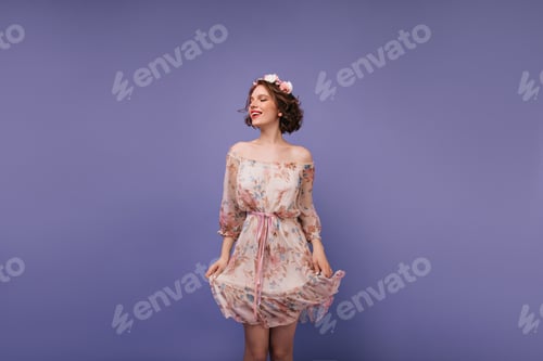 Preview: Joyful white girl playing with her romantic dress. Studio shot of magnificent curly lady with flowe