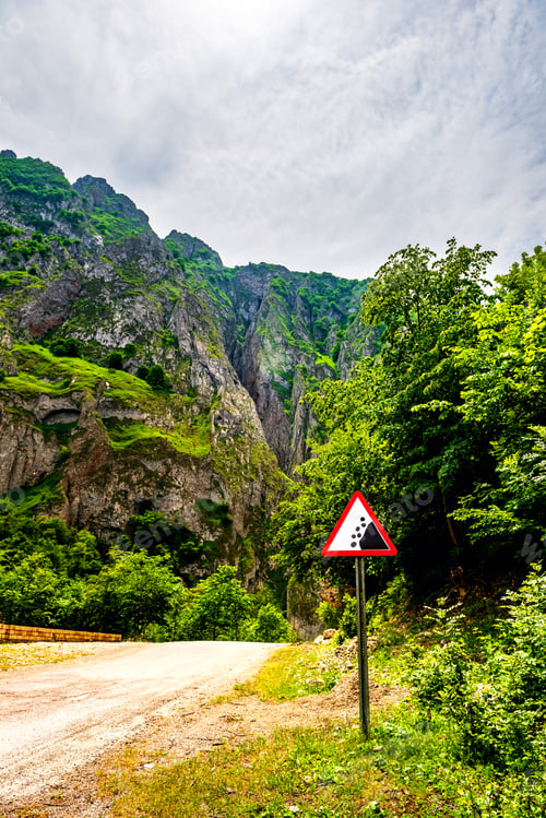 Preview: Road sign falling stones on road. Traffic sign caution possible falling rocks from the mountains