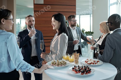 Preview: Three cheerful intercultural colleagues with champagne having discussion