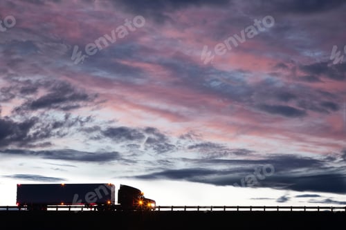 Preview: Silhouette of a commercial truck driving on a highway at sunset.