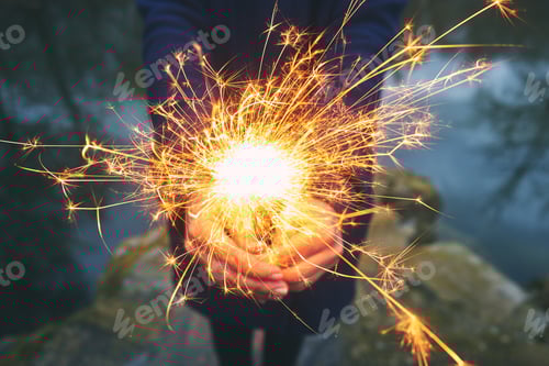 Preview: Woman holding sparkler in forest, winter day